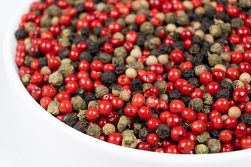 A mixture of different peppercorns on a white background