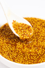 Traditional French Dijon mustard in a spoon on a white background