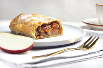 Pie with apple and dried apricot in a plate on the table