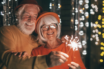 Cheerful caucasian senior couple holding sparklers celebrating new year. Happy lifestyle for mature retirees, party lights