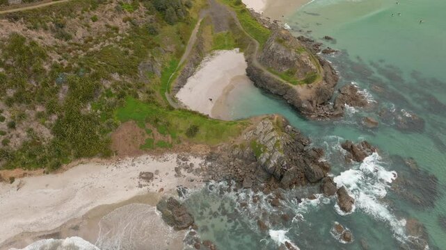 Rocky headland cove and the calm sandy Te Arai beach, Auckland, New Zealand.