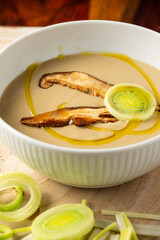 Top view of leek cream with dried mushroom on wooden table, vertical, with copy space