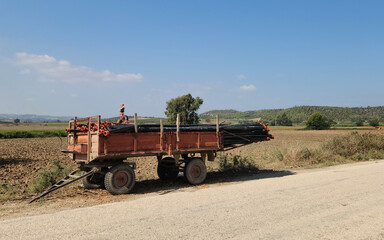 Obraz premium A tractor trailer loaded with irrigation pipes for sprinkler irrigation in a field