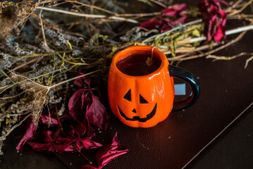 pumpkin shaped mug filled with tea on table next to dried flowers