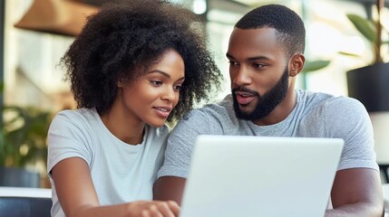 Man and woman sitting together, collaborating over a laptop, minimal background with copy space focusing on their discussion.