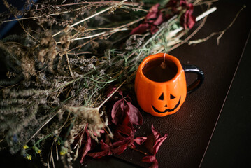 pumpkin shaped mug filled with tea on table next to dried flowers © Stepan