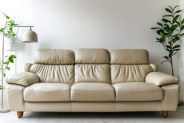 Fototapeta premium Beige leather sofa set against a white wall in a modern living room, accented by minimal plants and a contemporary lamp