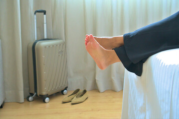 Traveler Relaxing on Bed with Suitcase in Background After Journey