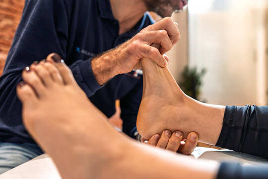 Osteopath performing ankle manipulation on patient during professional therapy session