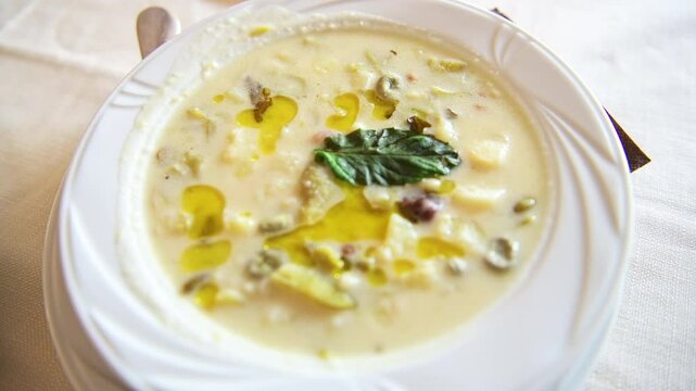 Sardinian vegetable soup local minestrone with green broad fava beans, potato, fregola pasta bacon cubes mint leaves on white plate, Sardinia Italy 
