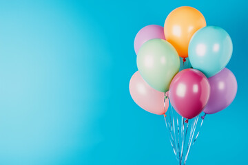 A bunch of colorful balloons on a blue background, with ample copy space.