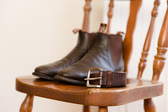 brown leather boots and belt on a wooden chair
