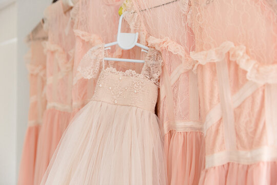 a flower girl dress hanging up with bridesmaid dresses