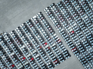 Aerial view of new cars stock at a large factory parking lot. Automotive industry, logistics...