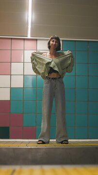 vertical shot. Beautiful girl unbuttoning her shirt at the subway station. style and fashion.