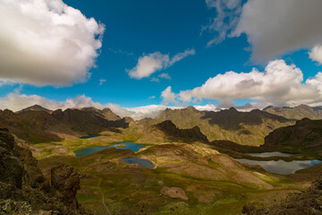Glacier lakes on the top of mountains and partly cloudy sky