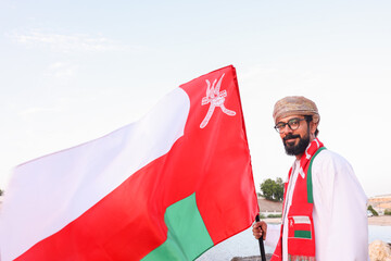 Omani man holding omani flag with a smile