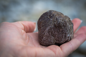 Dunkler Stein gehalten in einer Frauenhand