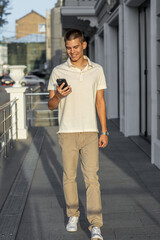 Full-length portrait of a young man on the street with a smartphone in his hand.