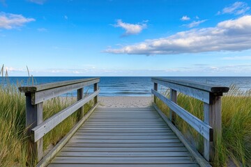 Obraz premium Wooden walkway leading to serene beach under a blue sky with clouds, perfect for relaxation or escape.