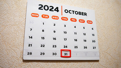 A wall calendar October page with a red frame cursor on Halloween date