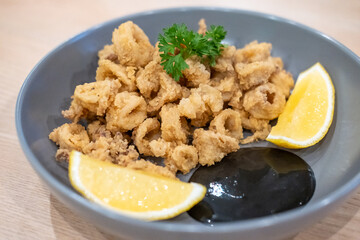 Close-up photo of Fried Squid or Calamari with lemon served on plate.