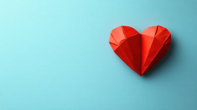 This handcrafted red paper heart contrasts beautifully against a soft light blue background, symbolizing love and creativity. The intricate folds highlight the artistry involved in making this charmin