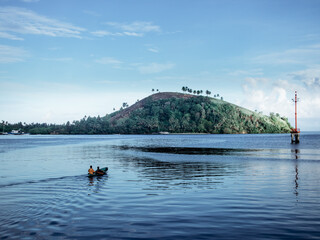 a man in a kayak is floating on a lake with trees on the hill in the background.