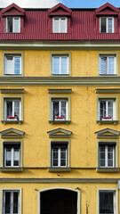 Bright yellow facade of a building with a red roof in an old European town looks like a dollhouse