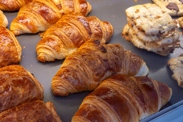 Fresh baked buttered croissants and sweet buns, pastries in village bakery in France