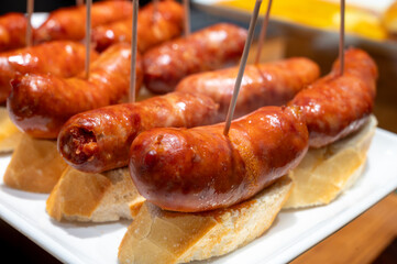 Typical snacks of Basque Country, pinchos or pinxtos skewers with small pieces of bread, fish, sea food, sweet green pepper served in bar in San-Sebastian or Bilbao, Spain
