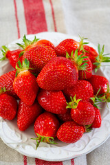 Plate with french organic red ripe sweet strawberries Fraises de Plougastel, harvested in France