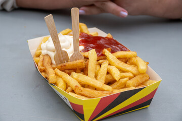 Belgian street and fast food, paper box in colors of Belgian flag with fried potato frit chips and...