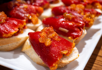 Typical snacks of Basque Country, pinchos or pinxtos skewers with small pieces of bread, fish, sea food, sweet green pepper served in bar in San-Sebastian or Bilbao, Spain