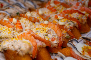 Typical snack of Basque Country, pinchos or pinxtos skewers with small pieces of bread, sea food, eggs, cheese, jamon served in bar in San-Sebastian or Bilbao, Spain, close up