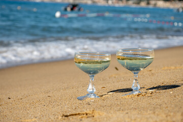 Summer time on French Riviera, two coupe glasses of champagne cremant sparkling wine on Pampelonne sandy beach near Saint-Tropez in sunny day, Var, vacation in France