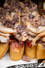 Typical snacks of Basque Country, pinchos or pinxtos skewers with small pieces of bread, fish, sea food, sweet green pepper served in bar in San-Sebastian or Bilbao, Spain