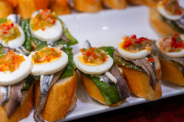 Typical snack of Basque Country, pinchos or pinxtos skewers with small pieces of bread, sea food, eggs, cheese, jamon served in bar in San-Sebastian or Bilbao, Spain, close up