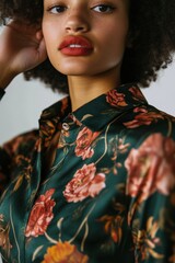 Fototapeta premium Fashion Portrait: A model with curly hair wearing a floral-patterned green shirt, showcasing vibrant colors for style inspiration.