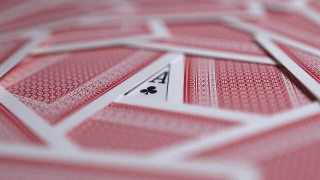 The sign from the ace of clubs with the other playing cards turned upside down. Poker gambling background. Smooth sliding and panning rotation.