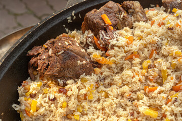 Pilaf with meat cooked in a large cauldron over an open fire. street food. Close-up