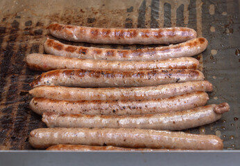 Hot dog sausages are fried on an outdoor barbecue. Close-up