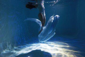 Woman diving with cloth underwater in the pool without face