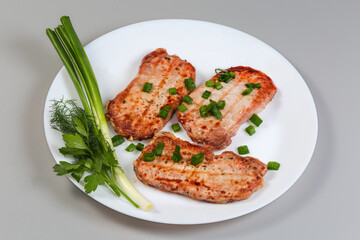 Grilled boneless pork chops with greens on the white dish