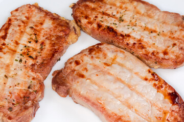 Grilled boneless pork chops with spices on dish, close-up