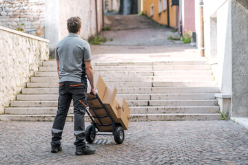 Delivery man pushing a hand truck and looking at stairs