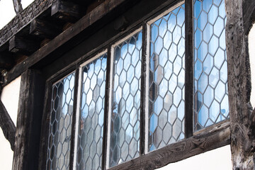 Historic old wooden window frames with glass reflection in historic tudor building