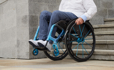 Part of an image of a man using a wheelchair who is unable to climb stairs