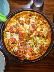 top view of pizza with mushrooms, tomatoes, capsicum and cheese in a pan