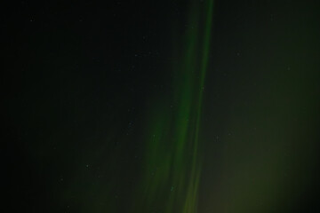  Soft green aurora borealis streaks gently across a starry night sky, creating a serene and...